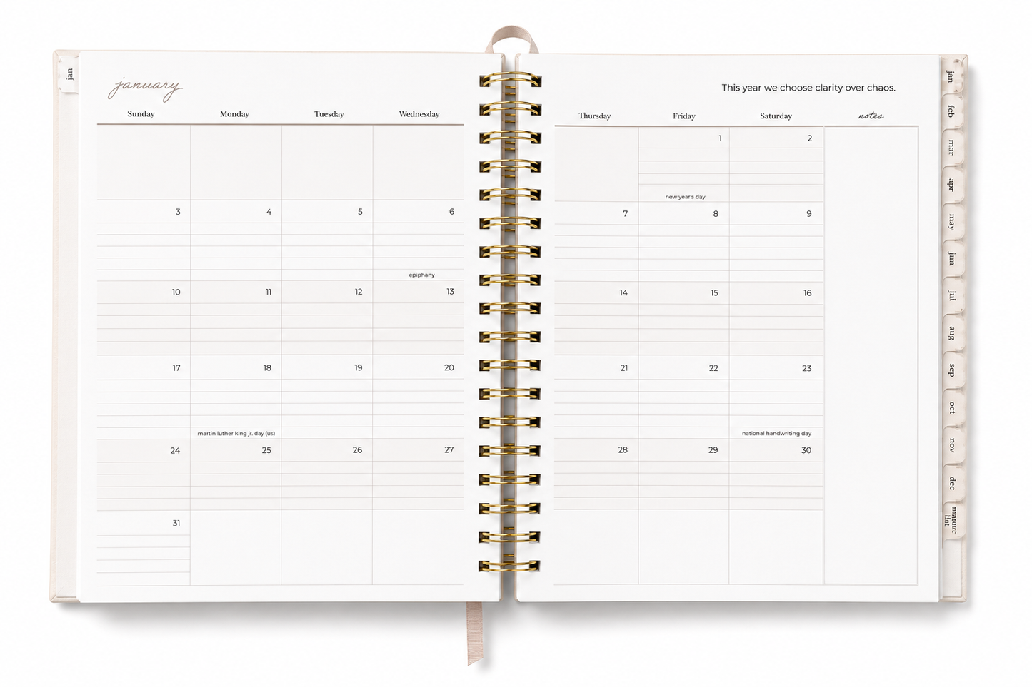 An open spiral-bound planner or calendar showing a monthly layout for January, with gold-toned rings and a ribbon bookmark, photographed on a clean white background.