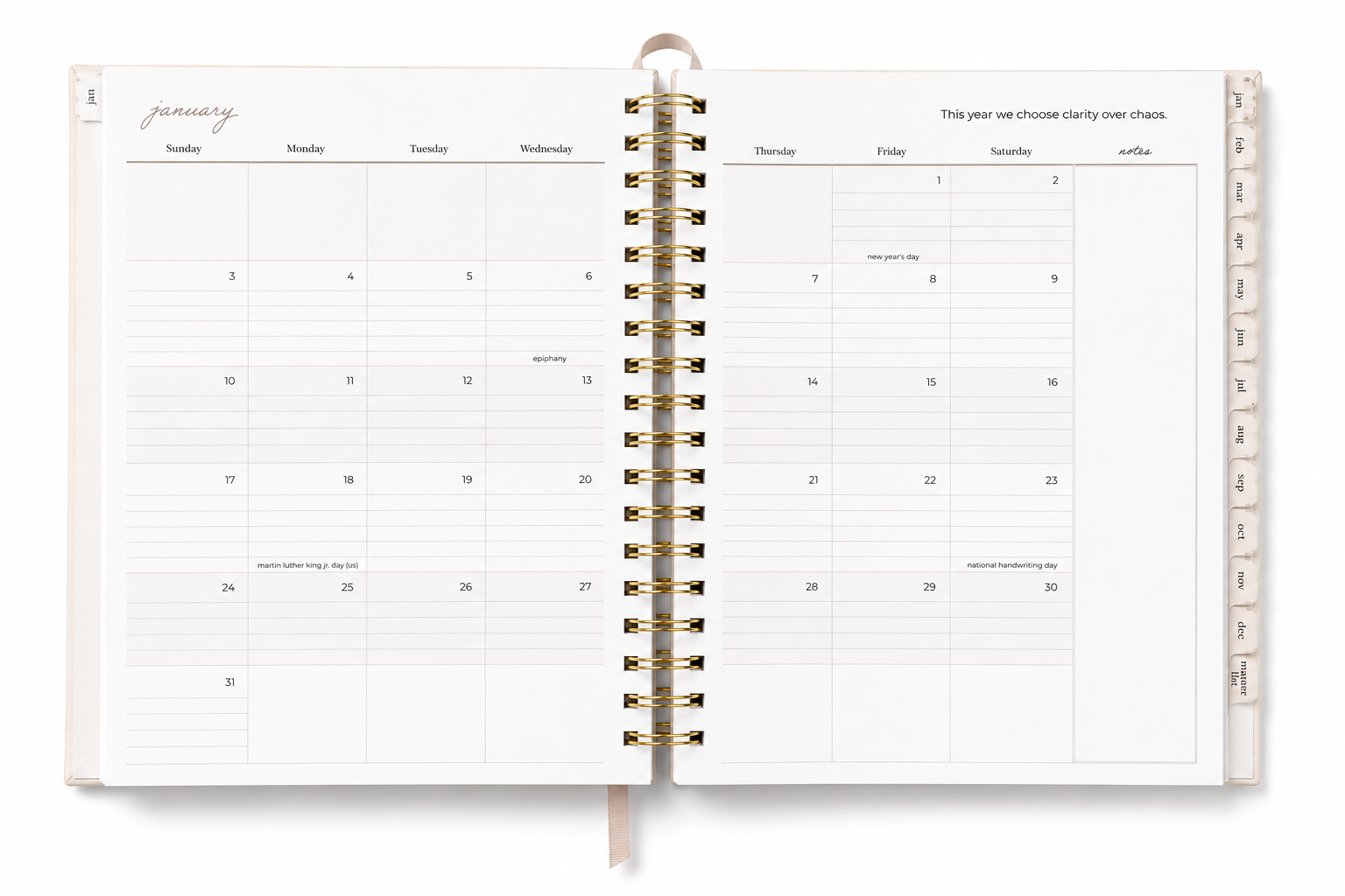 An open spiral-bound planner or calendar showing a monthly layout for January, with gold-toned rings and a ribbon bookmark, photographed on a clean white background.