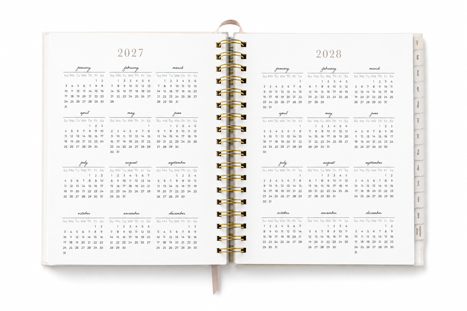 An open spiral-bound planner or calendar showing the years 2027 and 2028 with monthly grids printed in gray on white pages, with a gold wire binding and a ribbon bookmark.